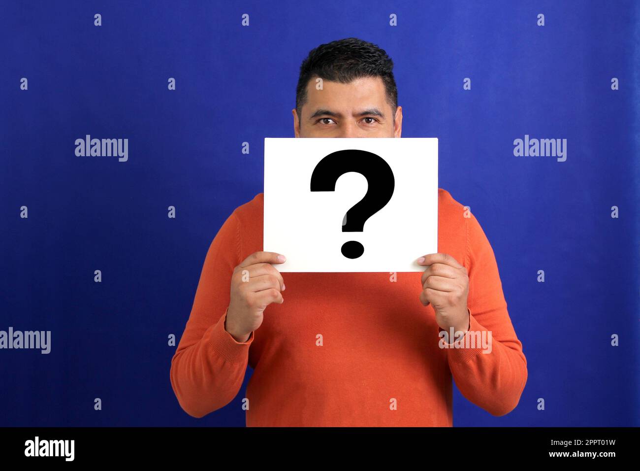 Latino brunette adult man shows a question mark, wonders, doubts, suspects, assumes, fears and distrusts Stock Photo