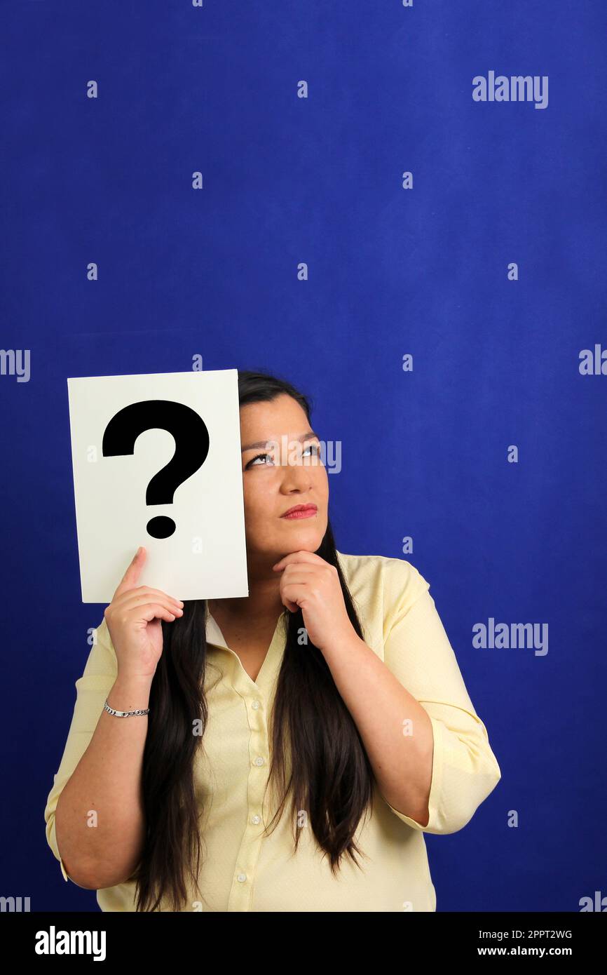 Latino adult woman shows a question mark, wonders, doubts, suspects, assumes, fears and distrusts Stock Photo