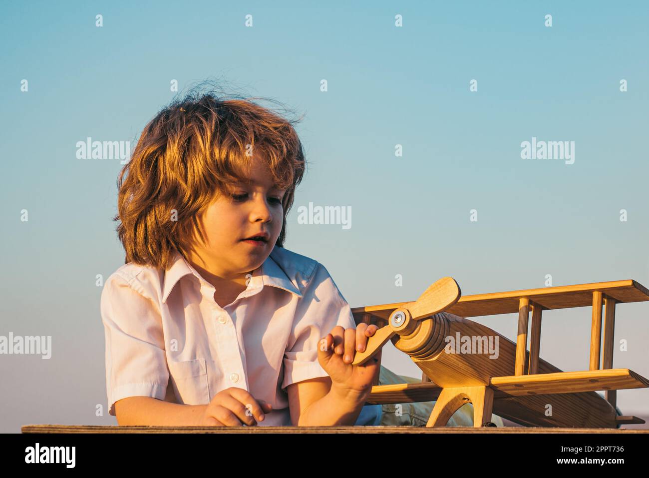 Child boy playing with wooden toy airplane, dream of a pilot