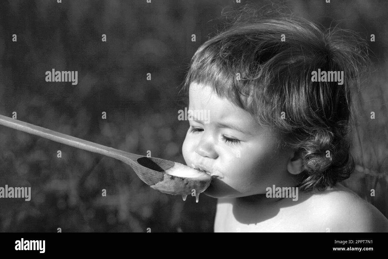 Feeding baby with big spoon outdoor on green grass Stock Photo - Alamy