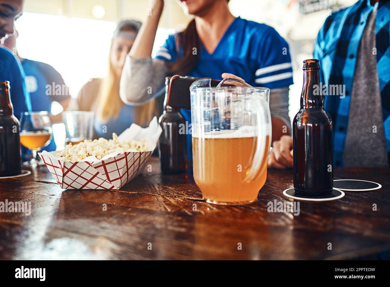 Its not a game without drinks and snacks. a jug of beer and popcorn on a counter at a sports bar. Stock Photo