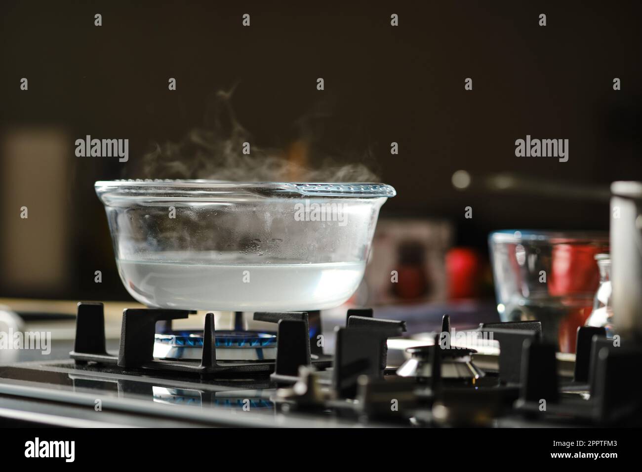 Process of boiling water in transparent casserole on gas stove Stock