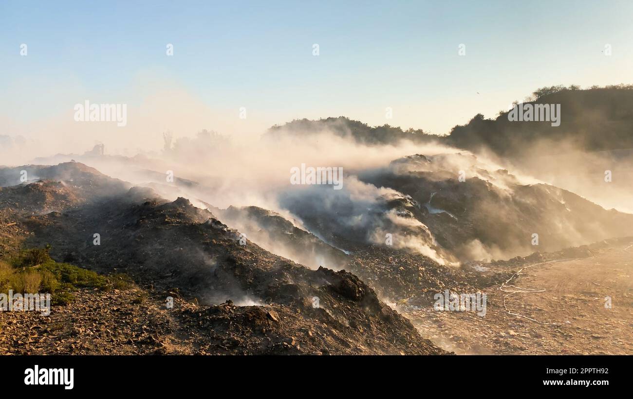Burning pile of garbage at dump ground or landfill releasing toxic