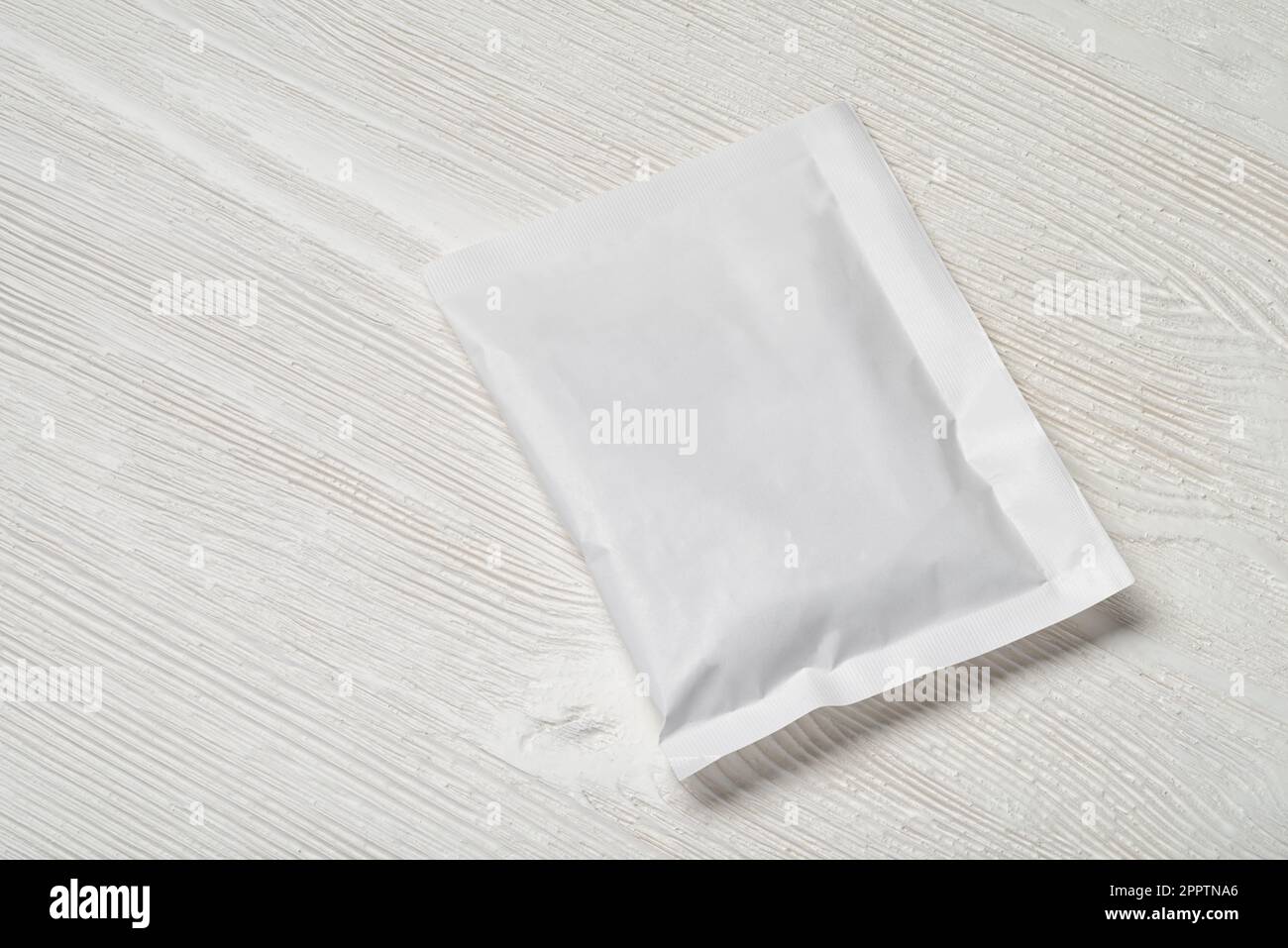 White blank paper sachet packet on wood table. Mockup template for