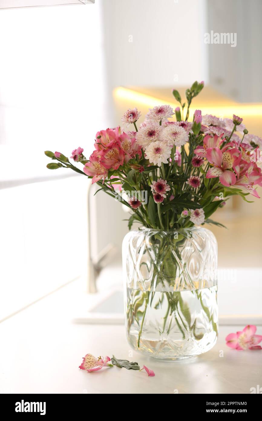 Vase with beautiful flowers on kitchen counter. Stylish element of