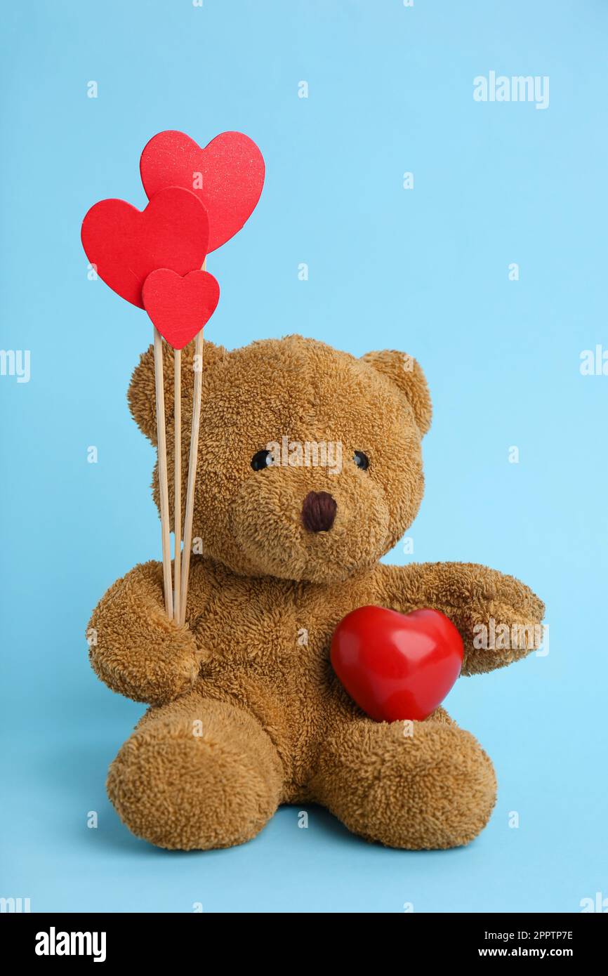 Cute teddy bear with red hearts on light blue background. Valentine's ...