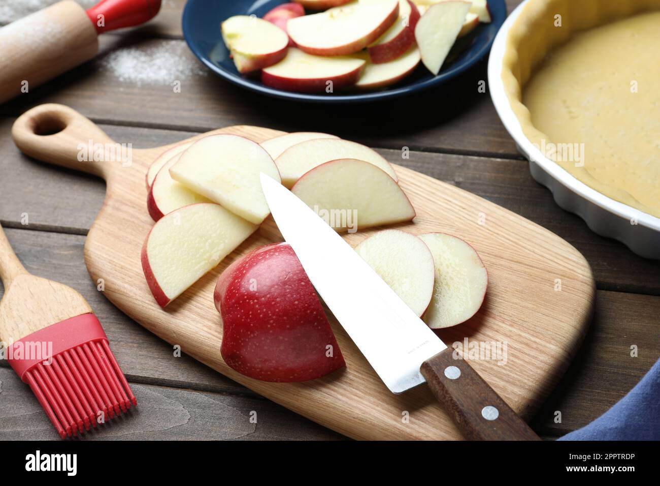 Cut fresh apple with knife and board on wooden table. Baking pie Stock Photo