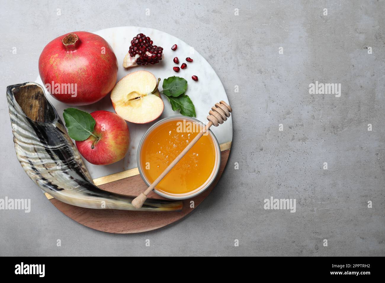 Honey, pomegranate, apples and shofar on grey table, top view. Rosh