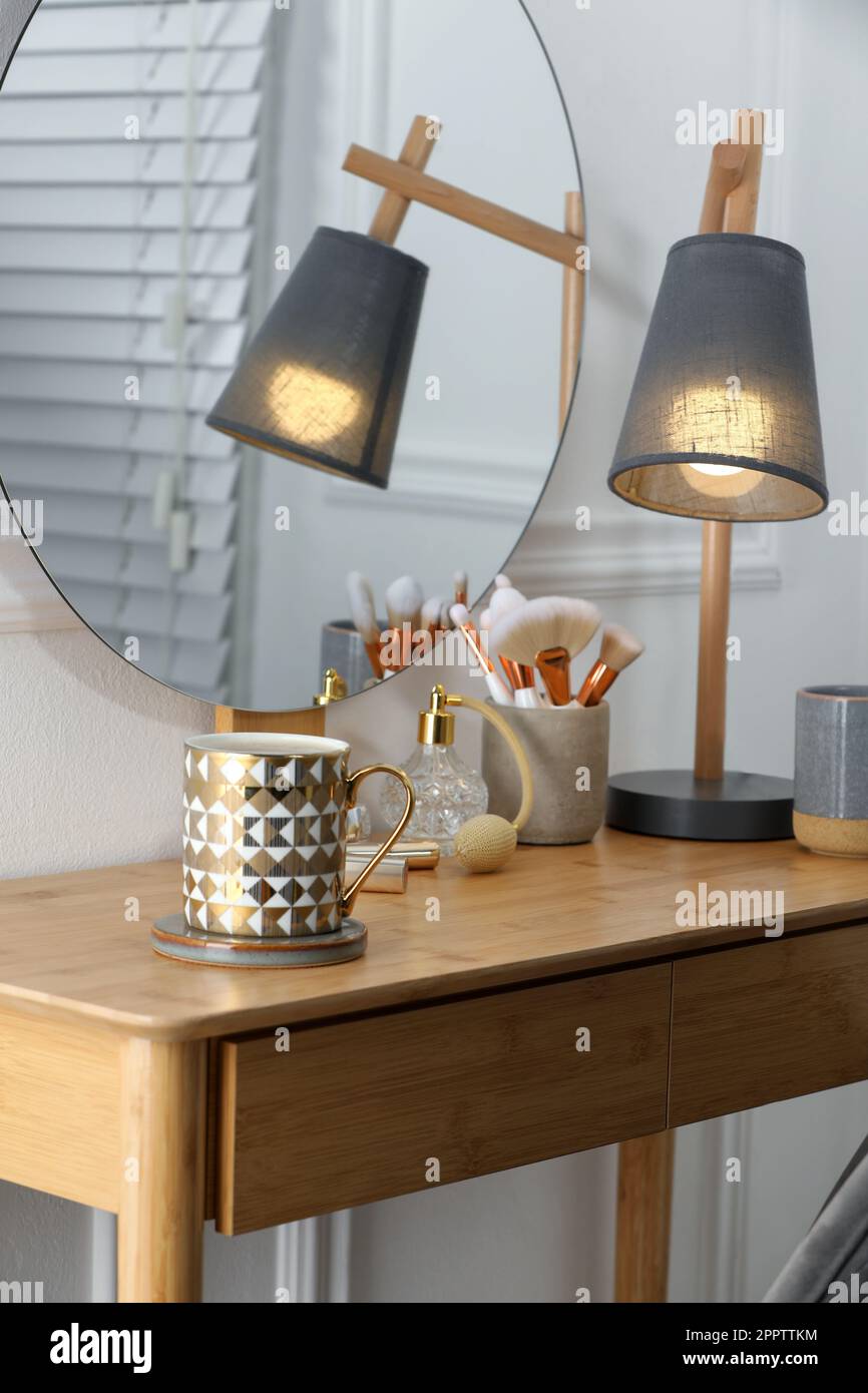 Mug of hot drink with stylish cup coaster on dressing table in room