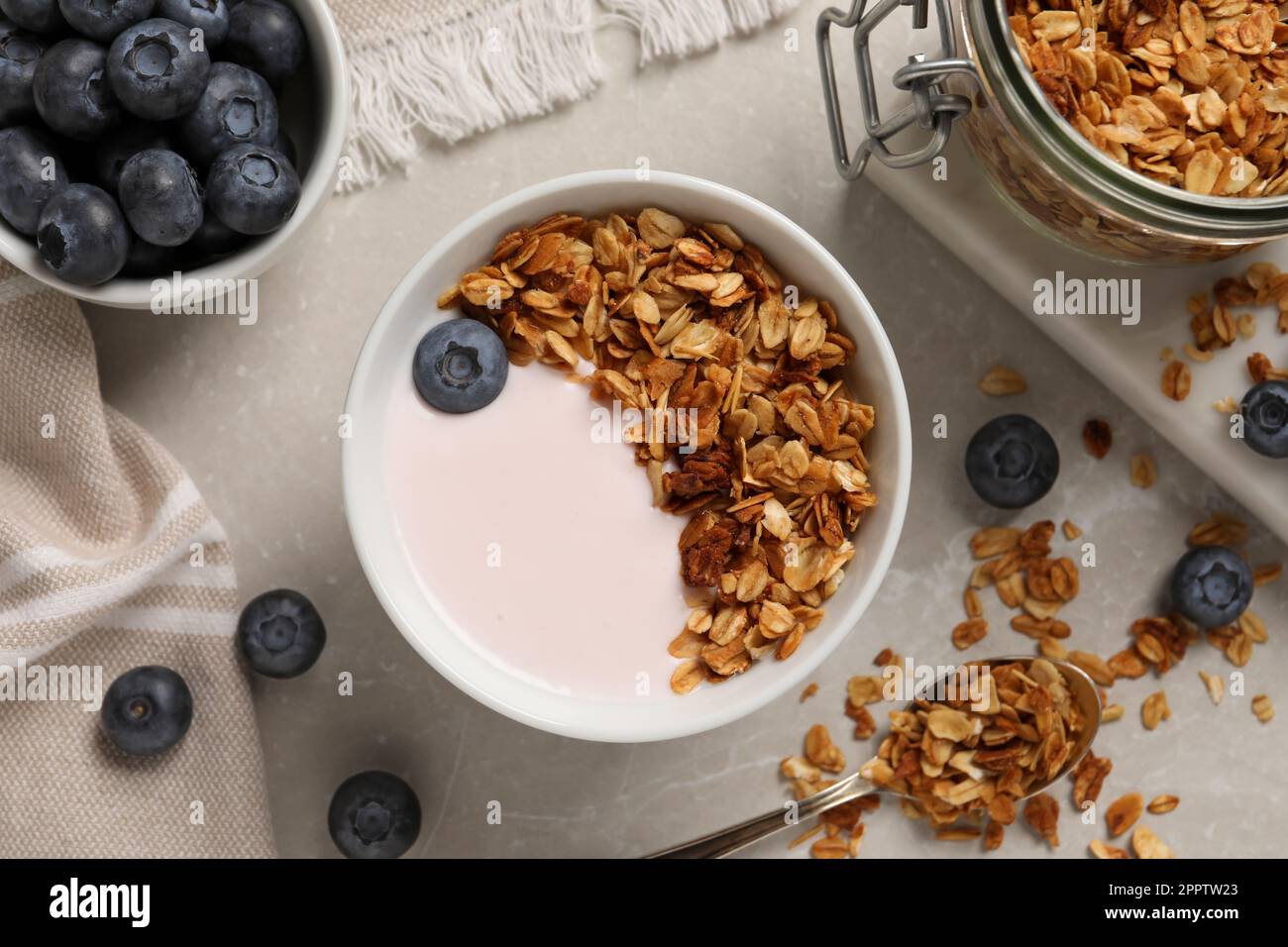 Delicious yogurt with granola and blueberries served on grey marble table, flat lay Stock Photo