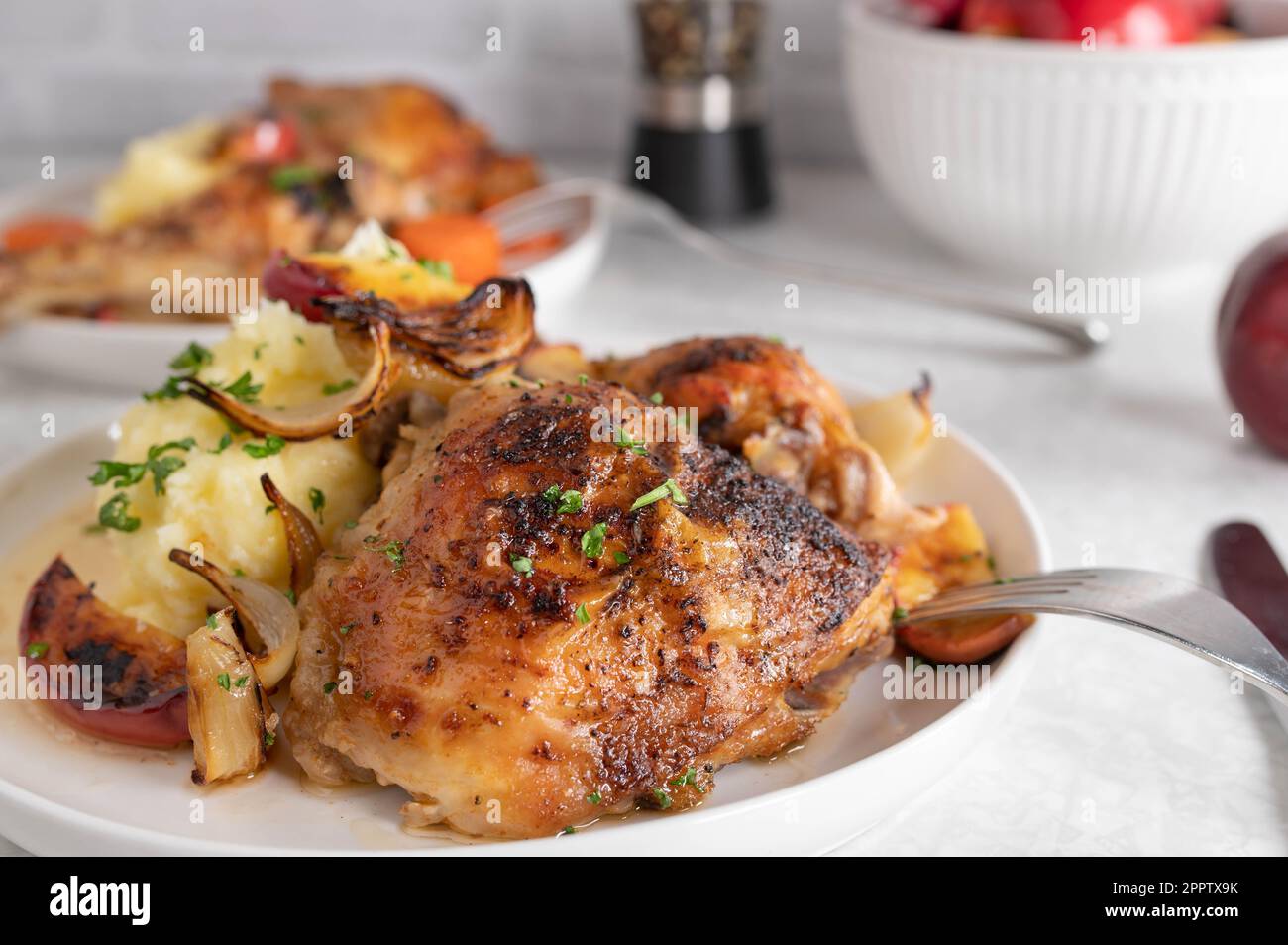 Baked chicken shanks with mashed potatoes, roasted onions and apples on a plate Stock Photo