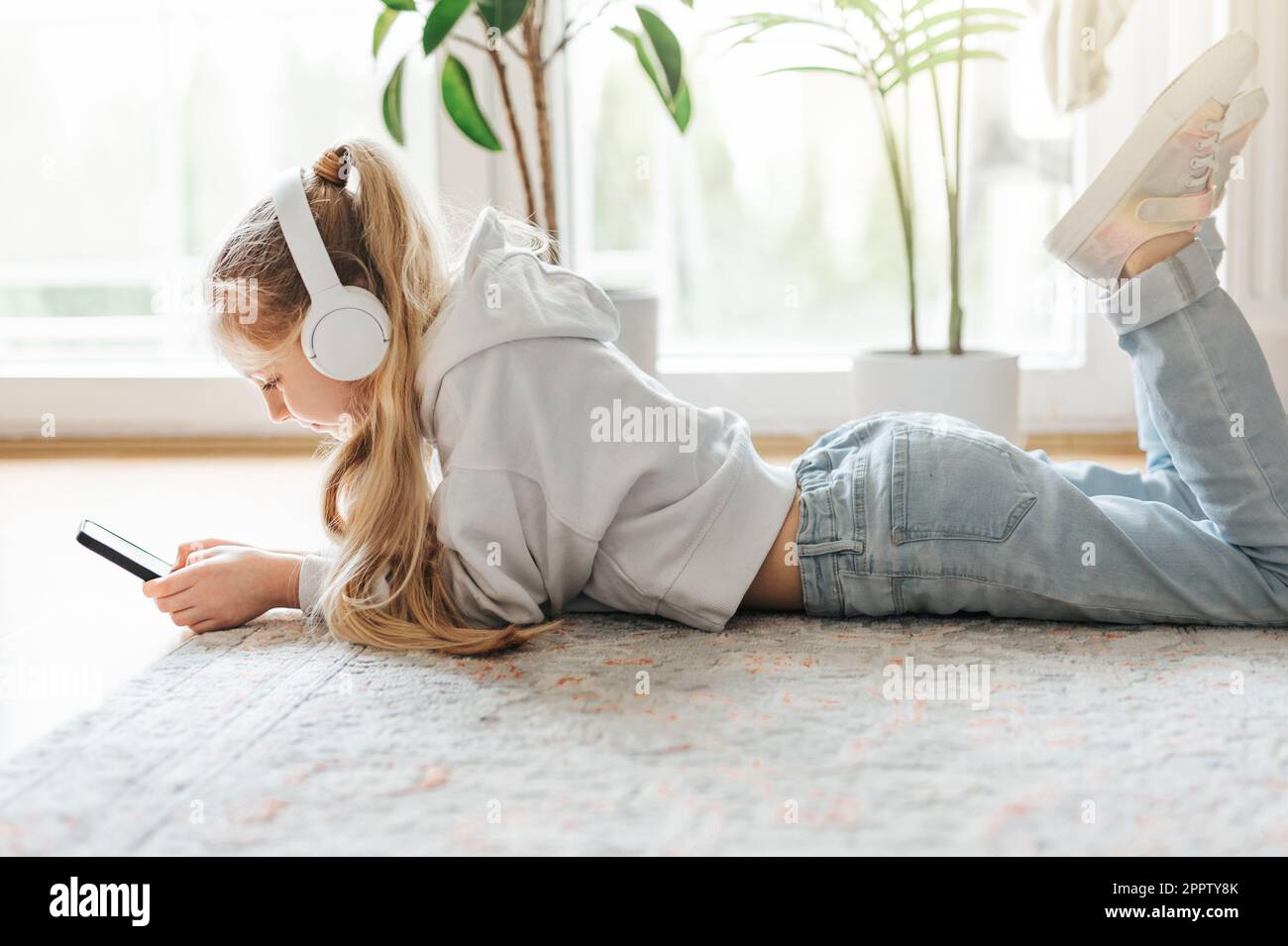 Smiling little girl listening music lying on the floor Stock Photo - Alamy