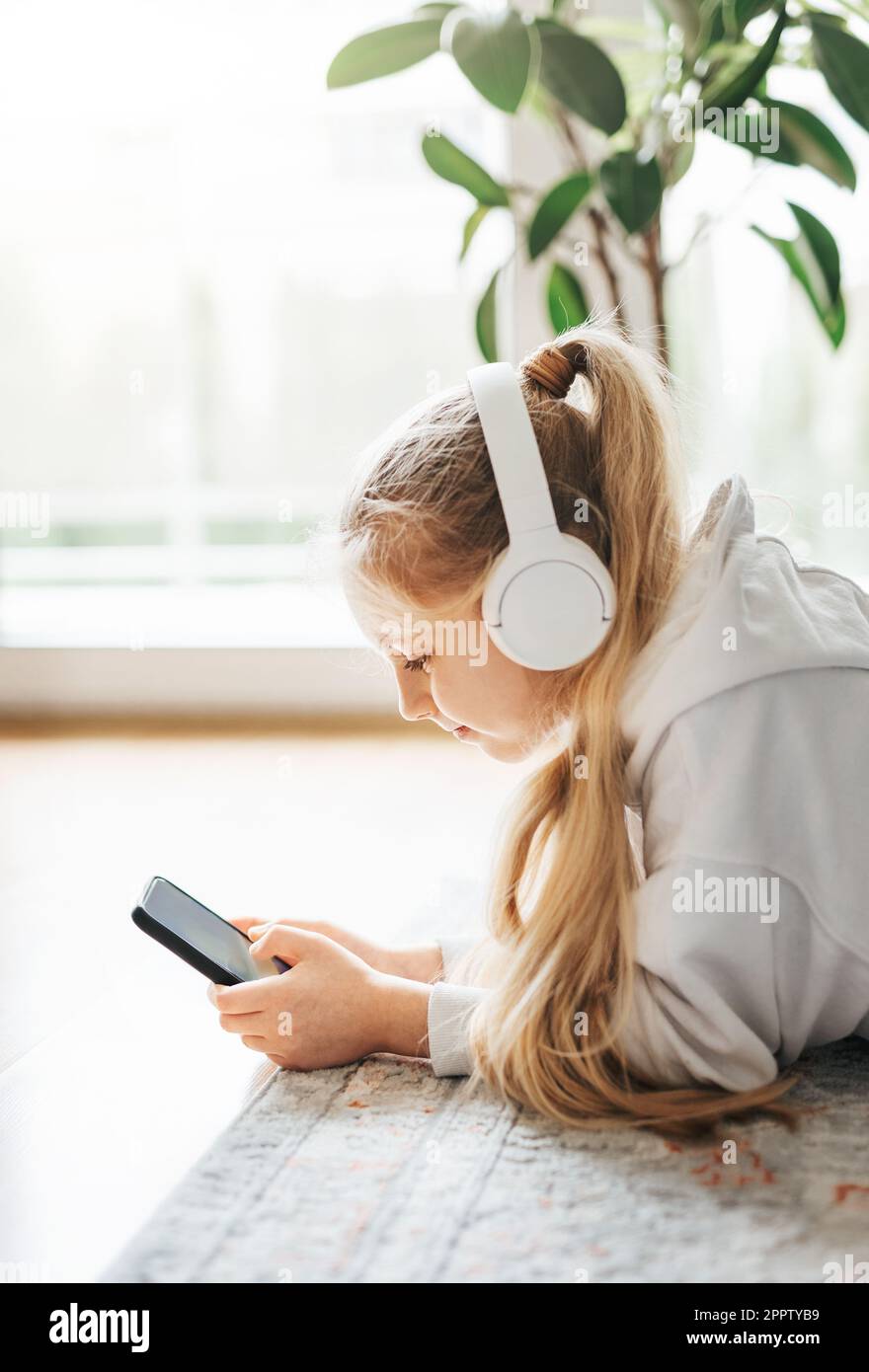Smiling little girl listening music lying on the floor Stock Photo - Alamy