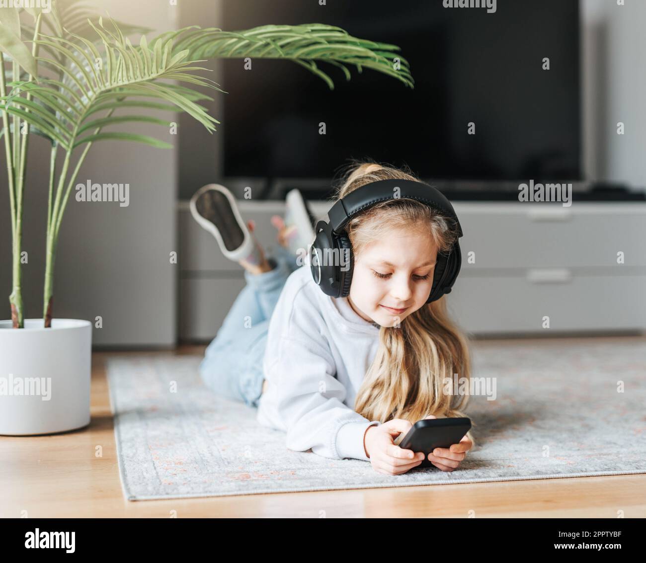Smiling little girl listening music lying on the floor Stock Photo - Alamy