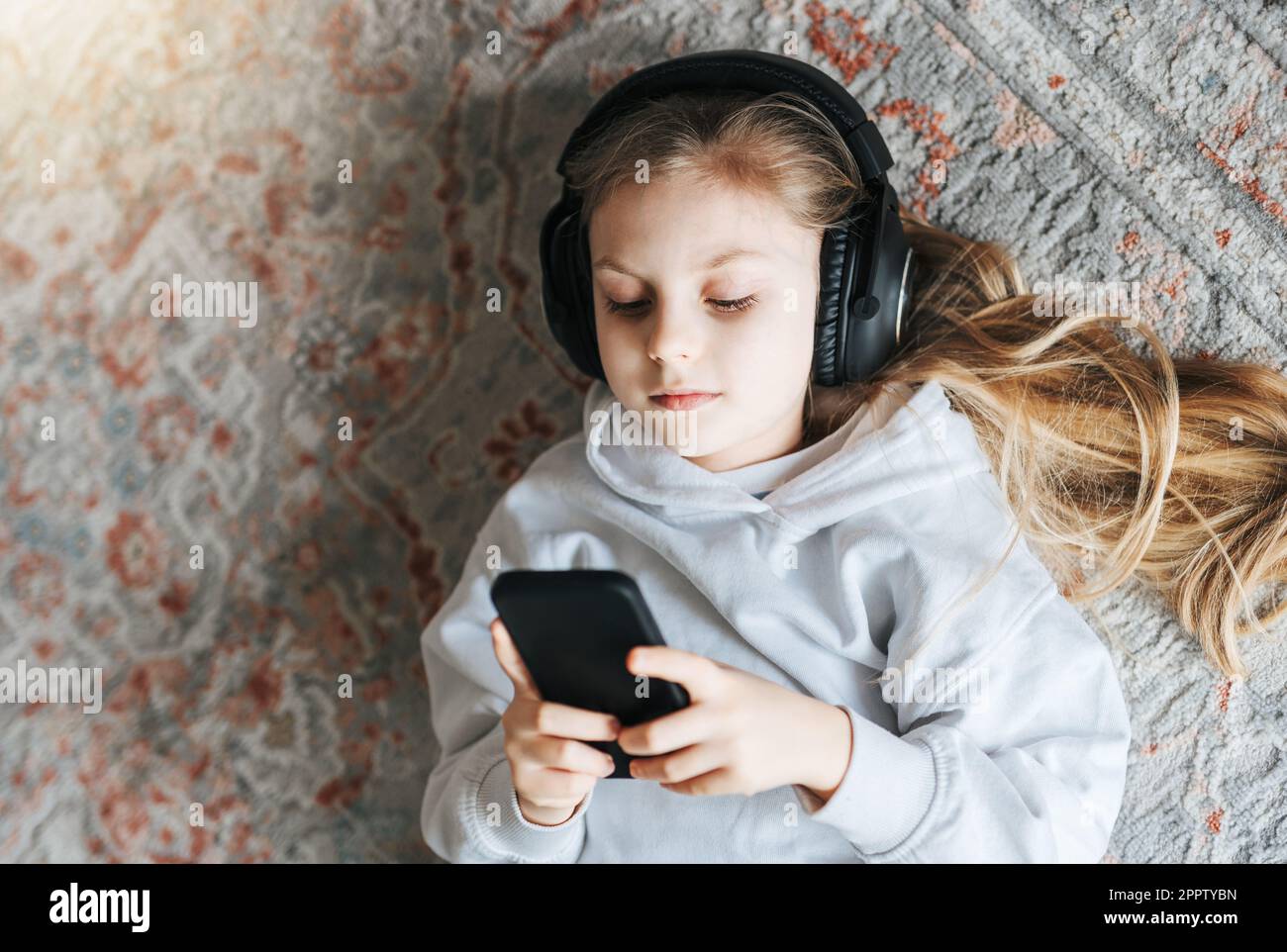 Smiling little girl listening music lying on the floor Stock Photo - Alamy