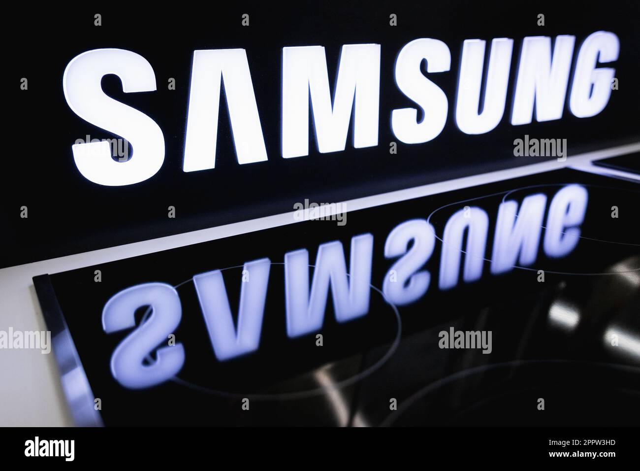 The SAMSUNG logo on the stand is reflected in the electric cooker in the store Stock Photo