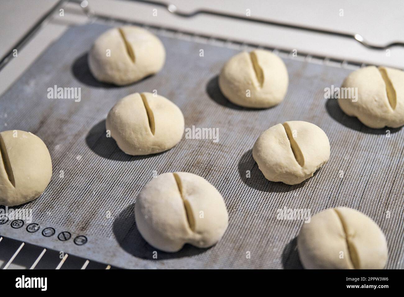 Cut bread roll dough on cookie sheet Stock Photo