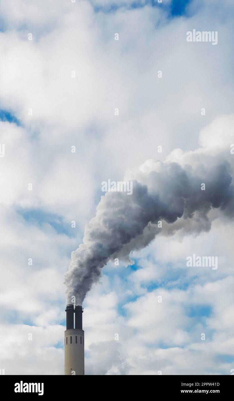Smoke cloud emitting from factory smokestack into sky Stock Photo