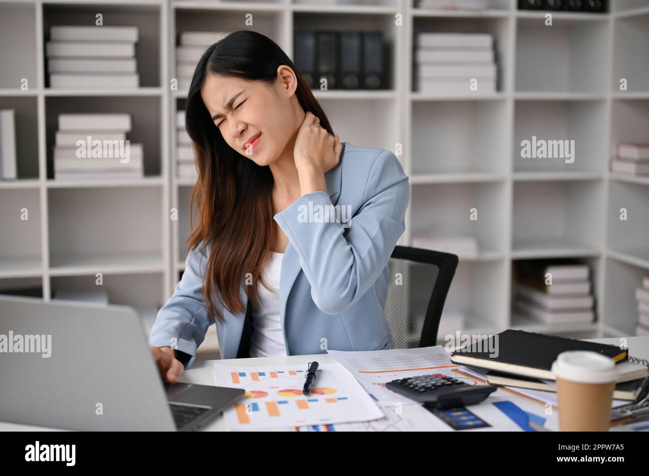 Overworked and tired millennial asian businesswoman sits at her office