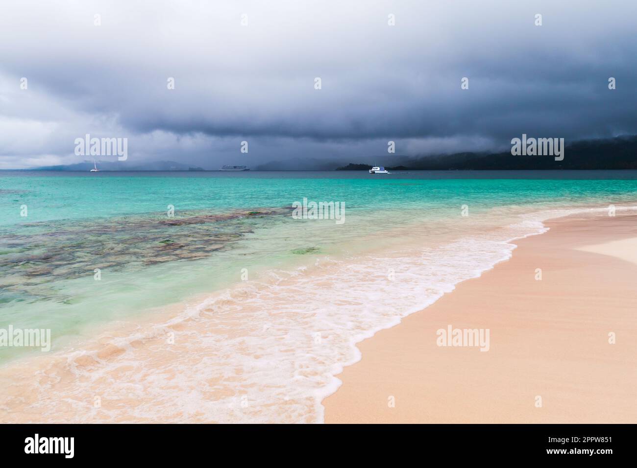 Empty beach with shore water. Coastal landscape with sea waves under dark dramatic sky. Atlantic ocean coast, Dominican republic, Samana bay Stock Photo
