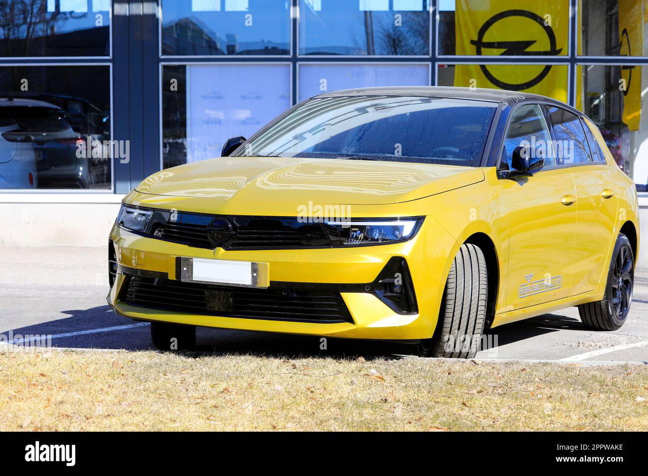 New, yellow Opel Astra parked outside a dealership. The new 6th generation of Astra is available with electric drive. Salo, Finland. April 10, 2023. Stock Photo