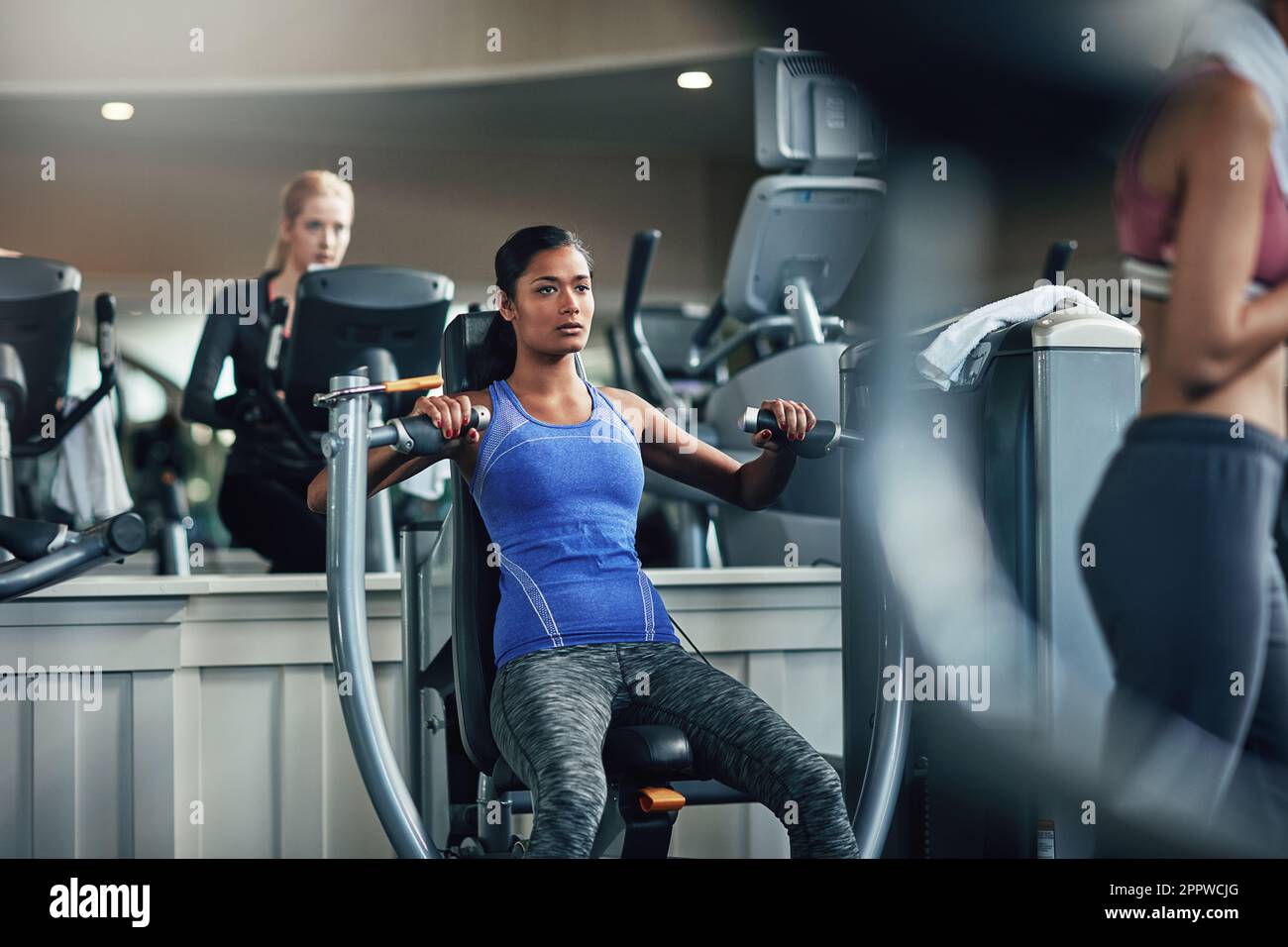 Young woman doing exercise on a chest machine fly in the gym. Women wear  sportswear flexing arm muscles on chest machine fly in gym Stock Photo