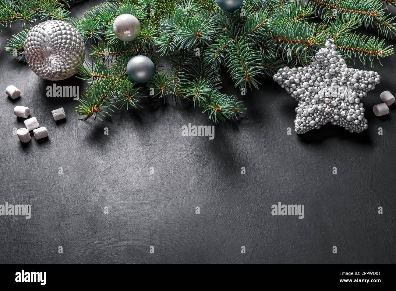 Christmas composition. Christmas decor, pine cones, fir branches, silver star and ornaments on black background, top view, copy space. Stock Photo