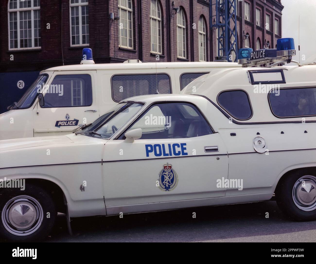 A 1981 historic image of two police vehicles parked in Wellington, the capital city of New Zealand. In the foreground is an X Series Ford Falcon utility (ute), possibly an XA or XB model with a cab on the back most likely in use as a patrol wagon. Behind it is a Ford Transit van Stock Photo