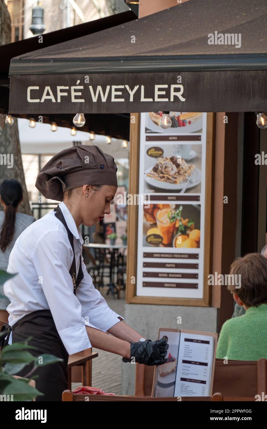 Majorca, Spain -30, March, 2023. A female waiter in uniform serves a table in cafe Sa Gelateria de Mallorca Stock Photo