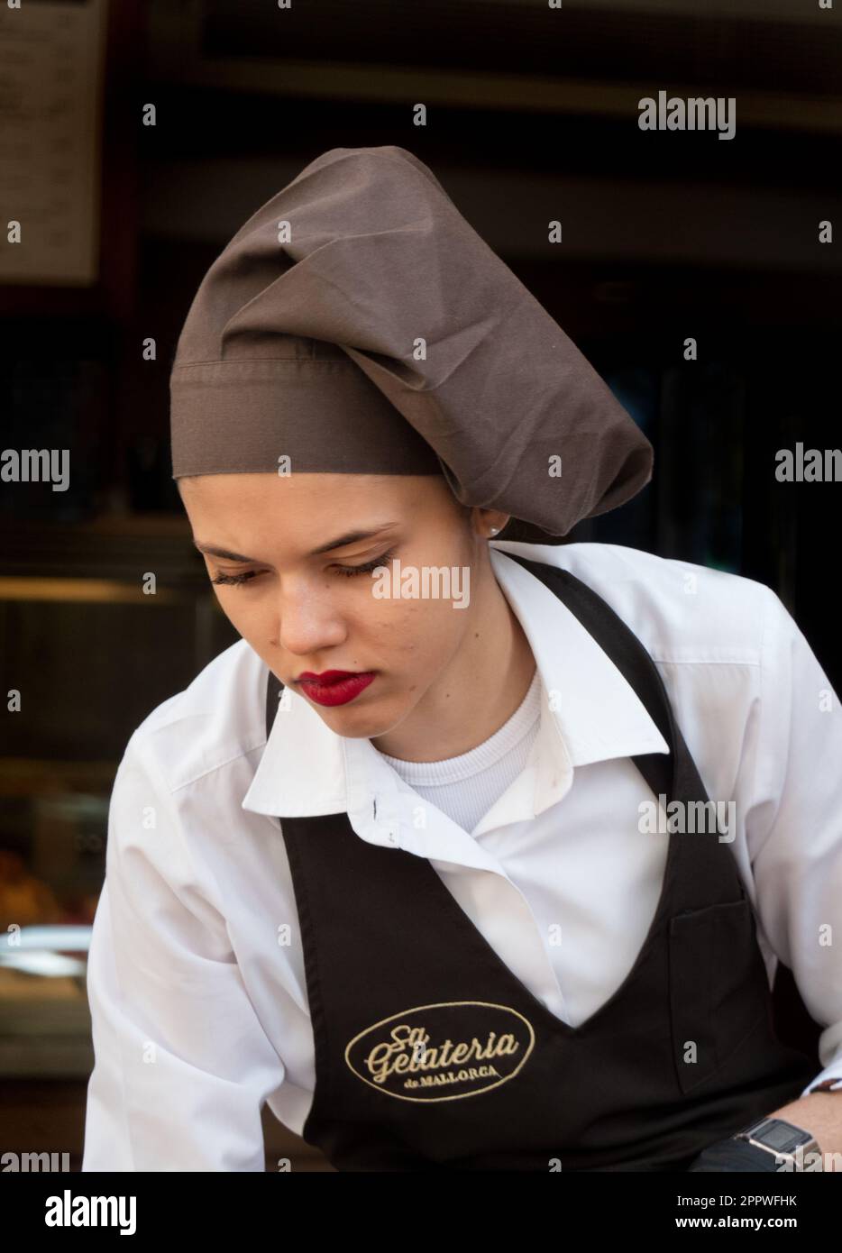 Majorca, Spain -30, March, 2023. A female waiter in uniform serves a table in cafe Sa Gelateria de Mallorca Stock Photo