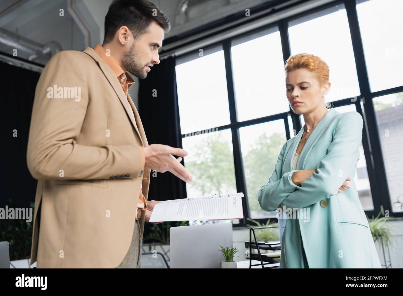 Pointing Near displeased businessman pointing at documents near upset woman crossing ...