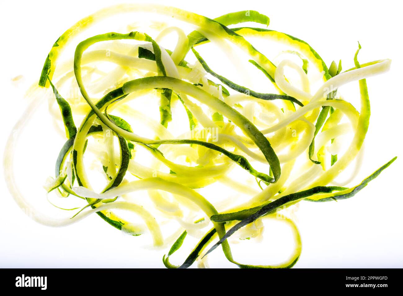 Zucchini zu Spagetti geschnitten und freigestellt mit viel licht gedreht auf einer Gabel und mit einem Basilikumblatt garniert Stock Photo