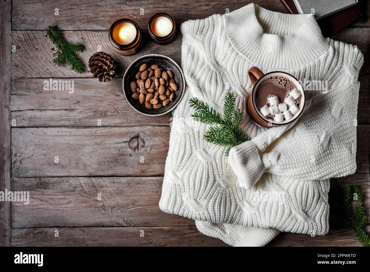 Hot coffee drink, almonds, cosy knitted sweater on wooden background
