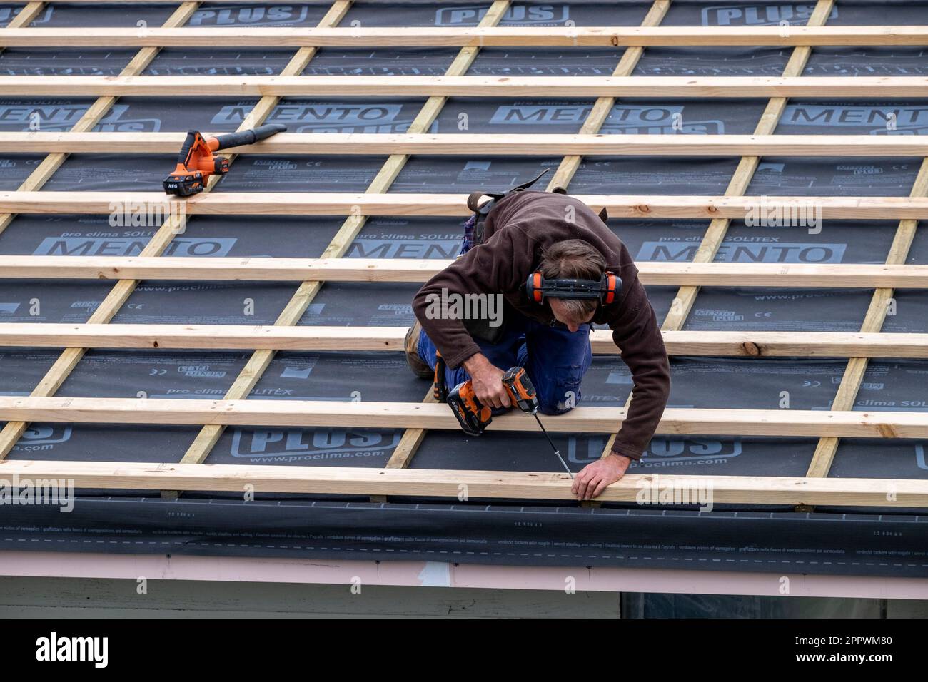 Tradesman fastening timber roof battens over insulation on a home