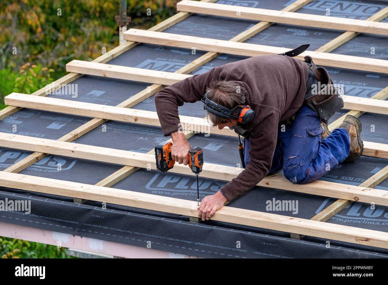 Tradesman fastening timber roof battens over insulation on a home