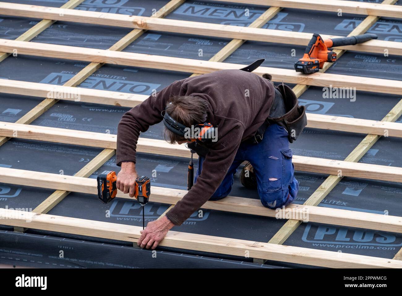 Tradesman fastening timber roof battens over insulation on a home renovation Stock Photo