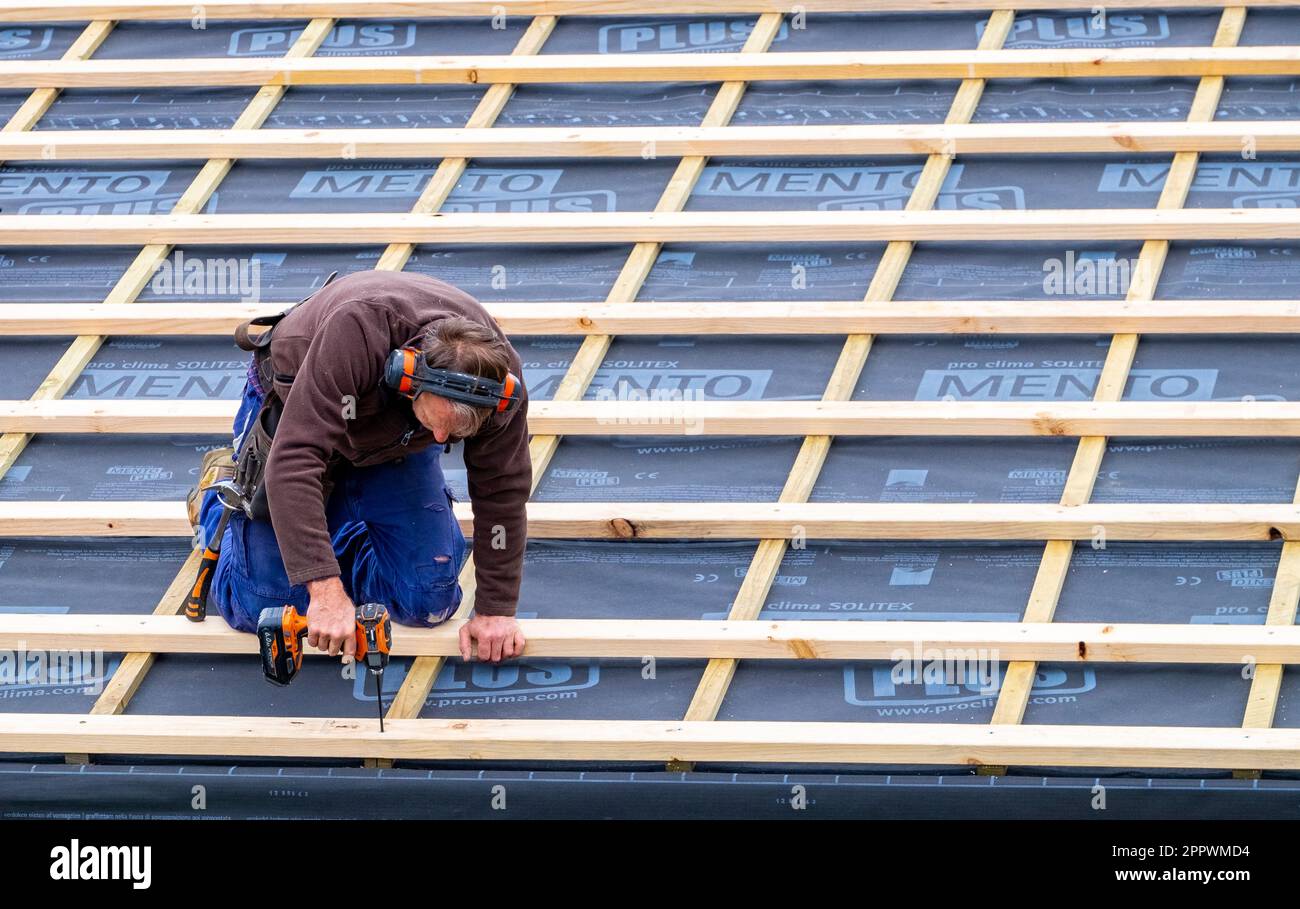 Tradesman fastening timber roof battens over insulation on a home