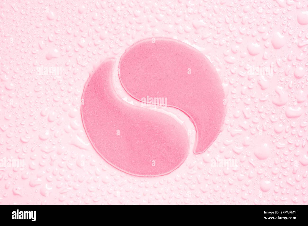 Hydrogel pink eye patches on pink background with water drops close up