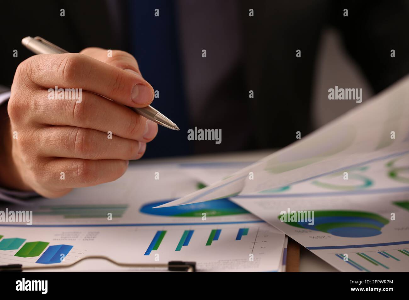 Businessman pen pointing at business document for chart and graph data ...