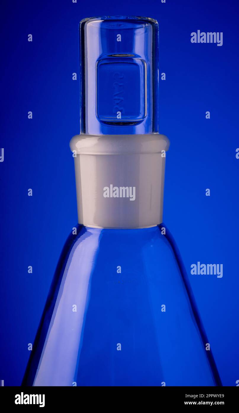 Closeup of a conical glass chemical flask seen against a blue background. Stock Photo