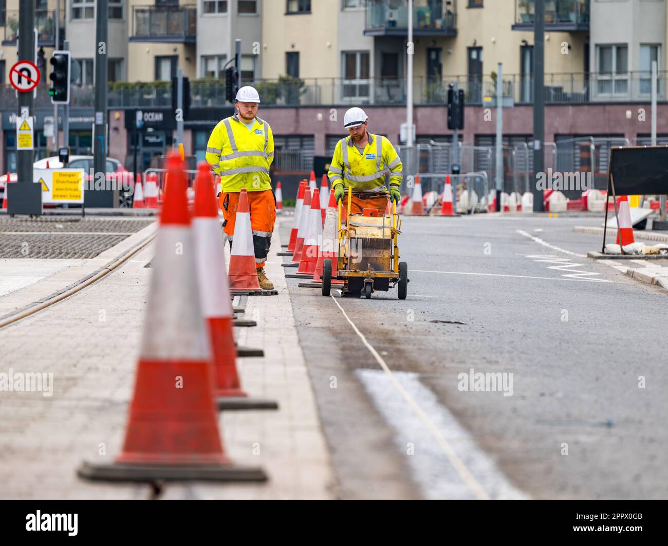 Two workmen painting white lines on roadside next to tram tracks, Leith, Edinburgh, Scotland, UK Stock Photo