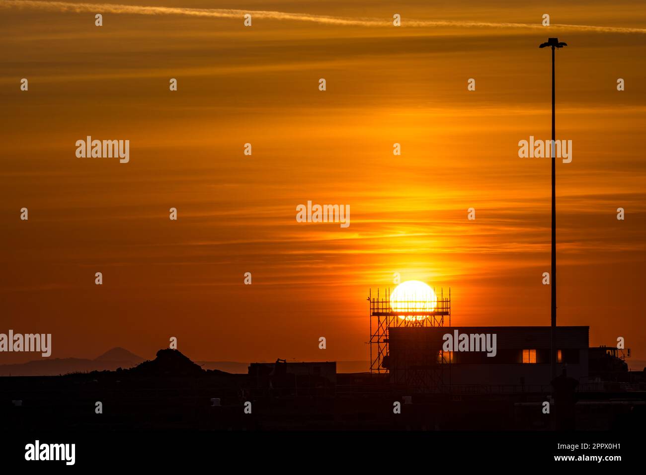 Sun rising above industrial metal structure, at sunrise, Leith Harbour, Edinburgh, Scotland, UK Stock Photo