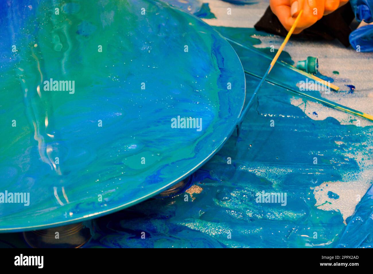 The process of creating a home-made trendy abstract modern pattern painted  with a brush of acrylic blue multi-colored resin on a round wooden board  Stock Photo - Alamy