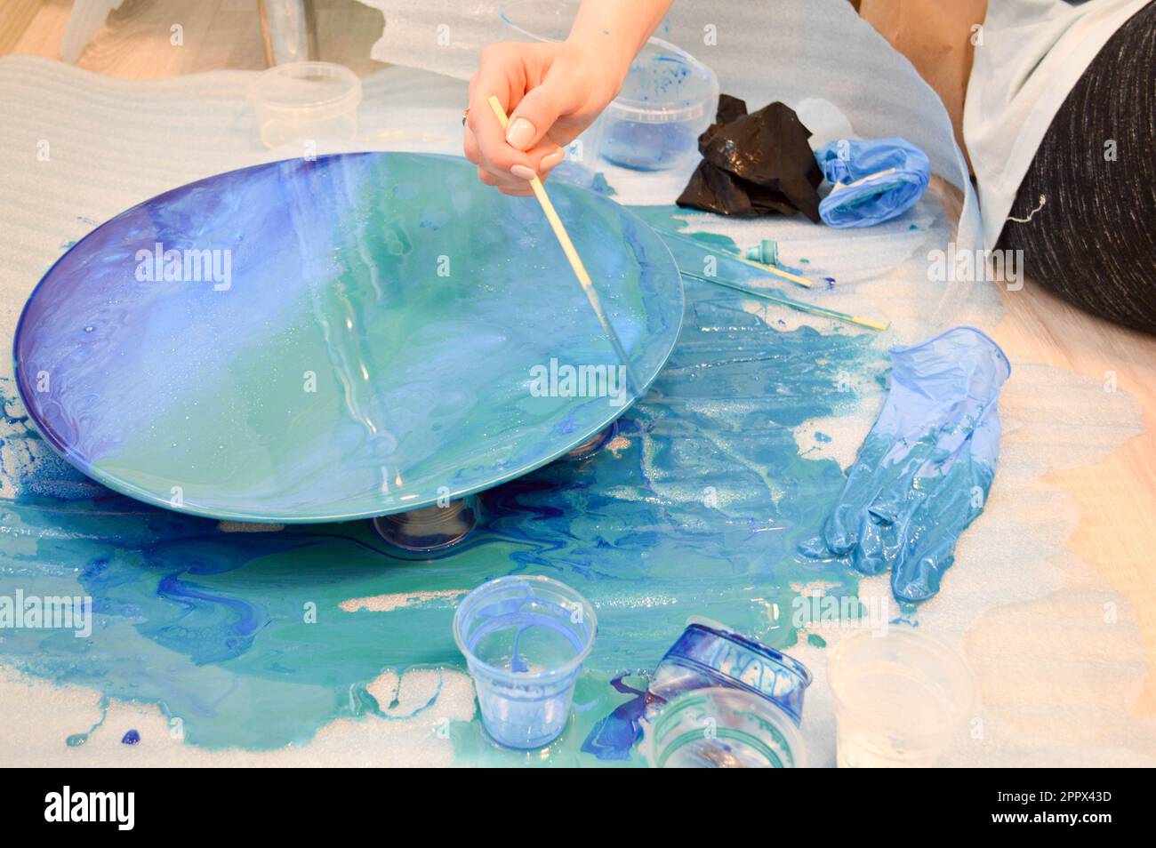 The process of creating a home-made trendy abstract modern pattern painted  with a brush of acrylic blue multi-colored resin on a round wooden board  Stock Photo - Alamy