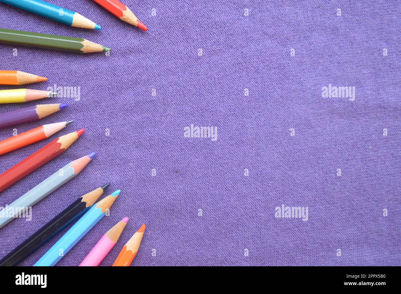 https://c8.alamy.com/comp/2PPX5B0/multicolored-bright-colorful-pencils-for-drawing-on-the-left-by-an-arc-and-a-place-for-your-text-on-a-background-of-purple-cloth-2PPX5B0.jpg
