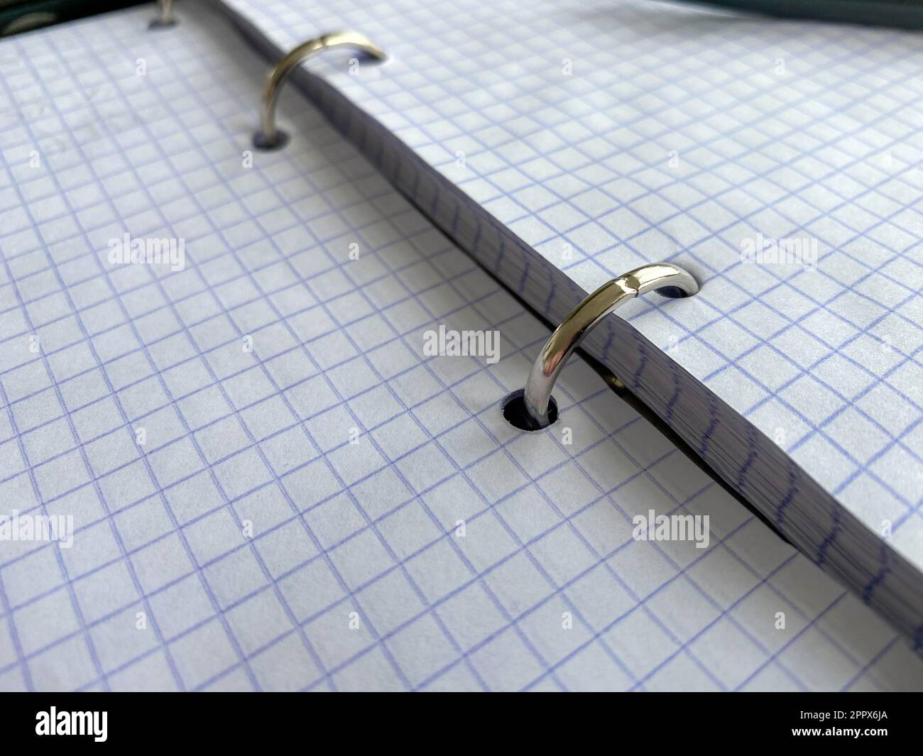 A writing pen rests on a notepad with squared paper sheets on a work desk with stationery in a business office. Stock Photo