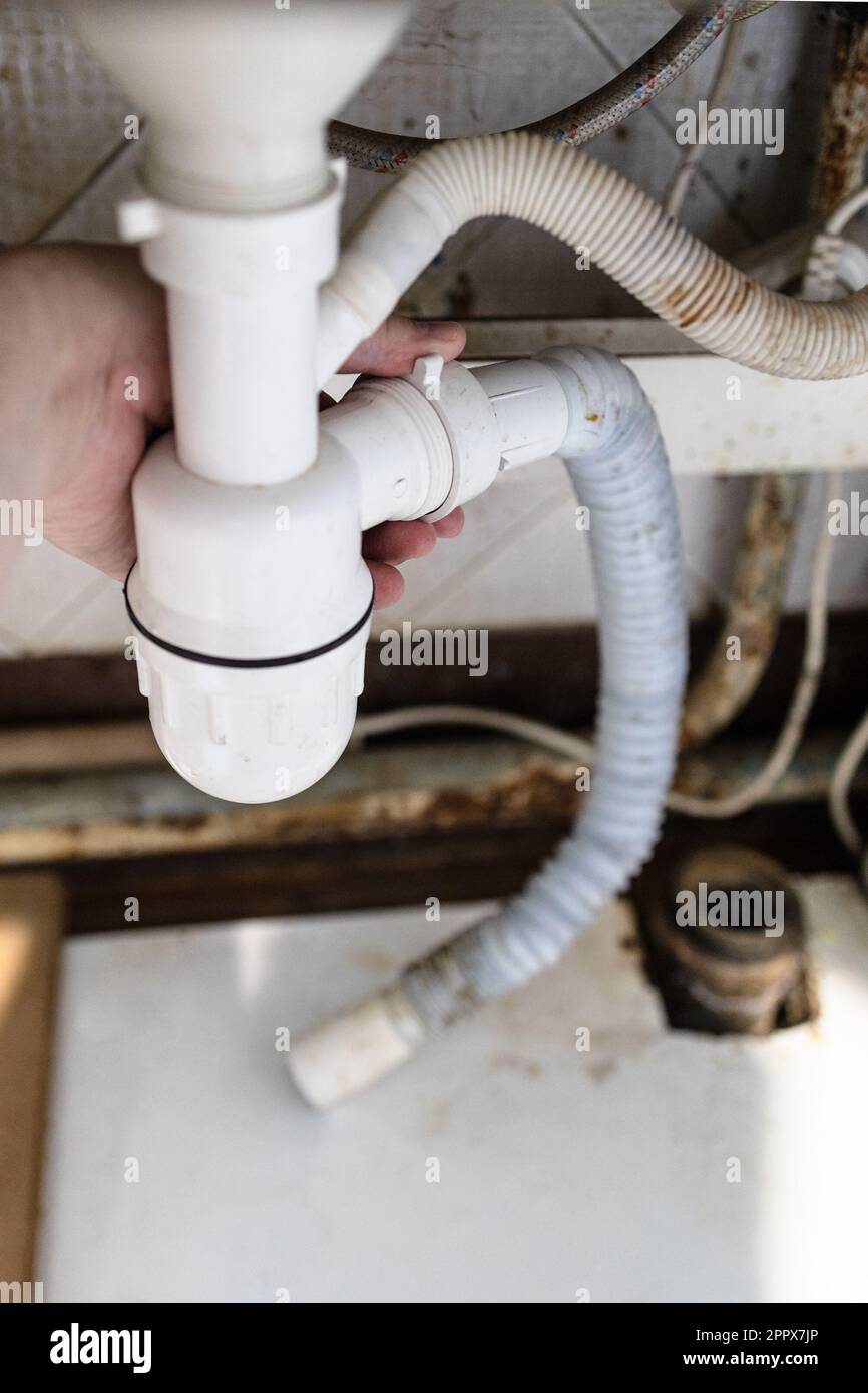 plumber disassembles old plastic siphon with drain corrugated hose near