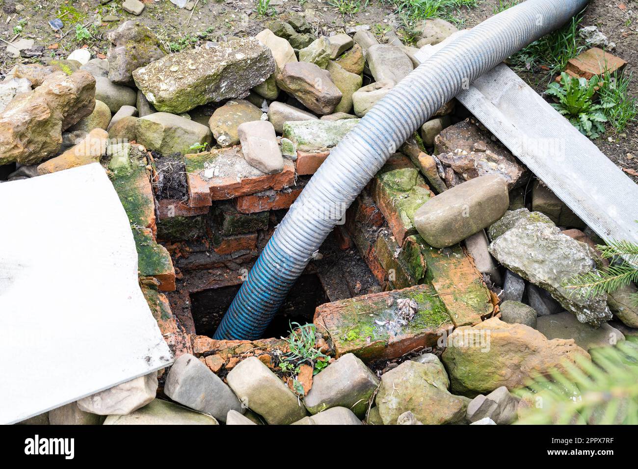 corrugated hose pumping out underground septic tank in village yard