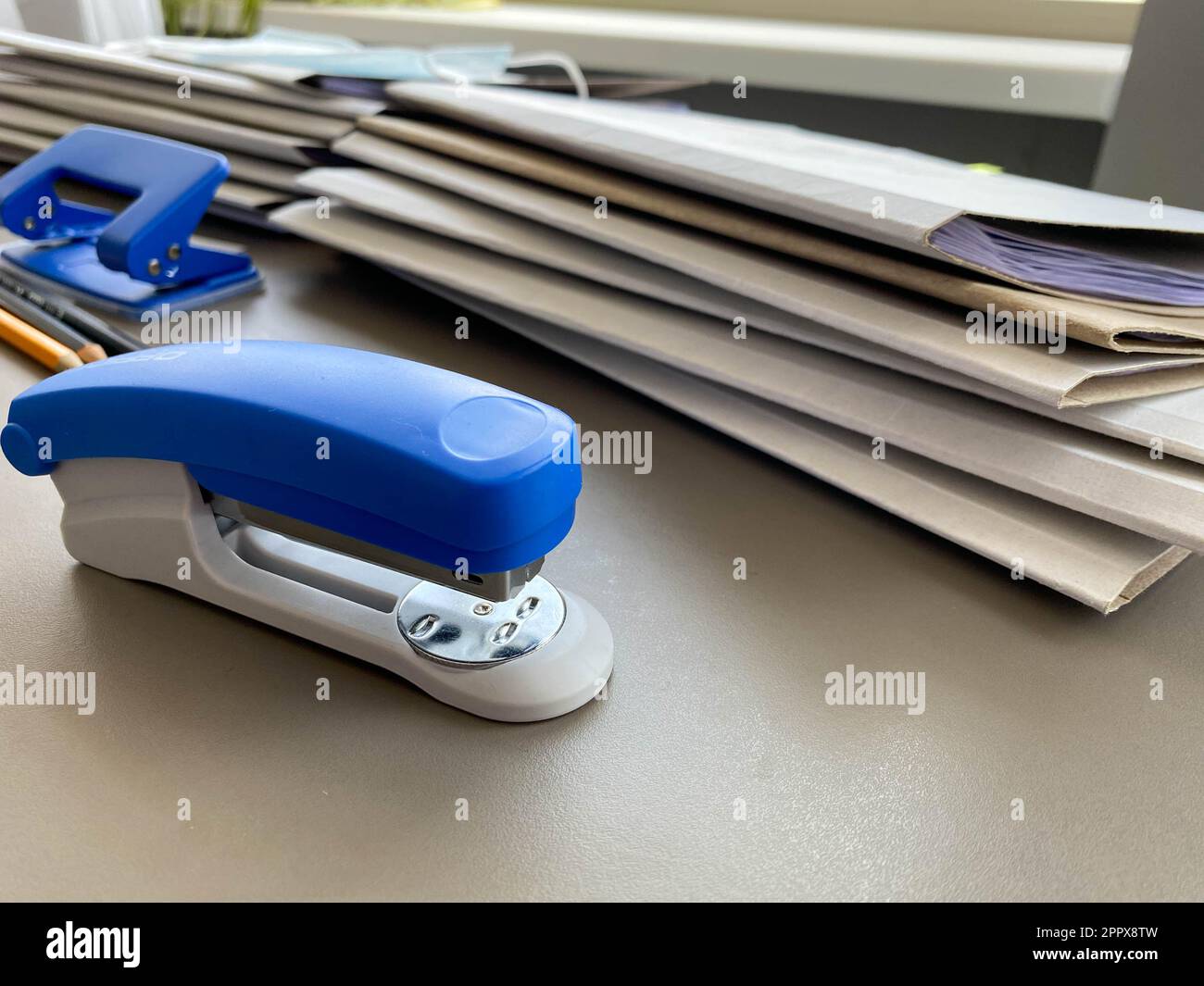 A large blue stapler for stapling paper lies next to the folders of ...
