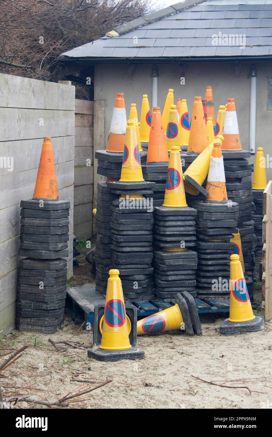 Piles of road traffic cones stacked up in a corner by a fence, West